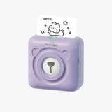 PeriPage A6 Mini Printer in purple, printing a cute 'Hello' design on a sticker. Showcasing the versatility and fun of this inkless mini printer for photo, label, and note printing